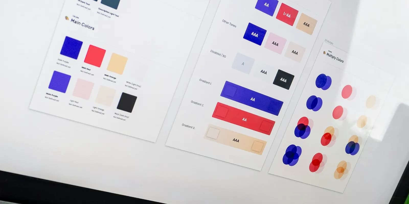 A desk with a tablet showing colour swatches, printed design sheets and a keyboard.
