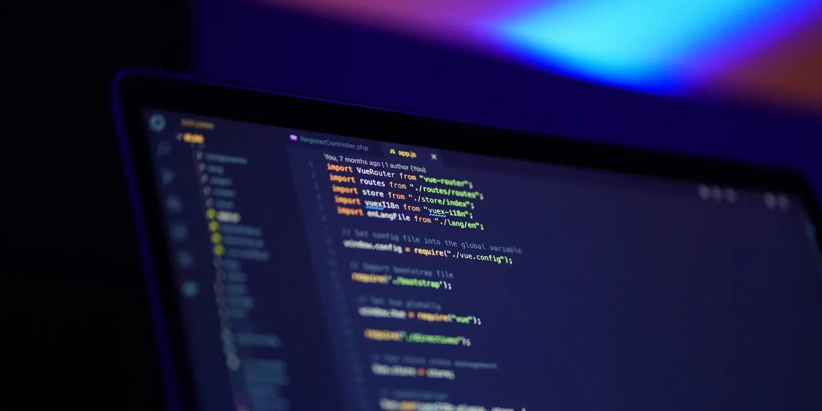 A laptop screen filled with source code, photographed in a dark room.