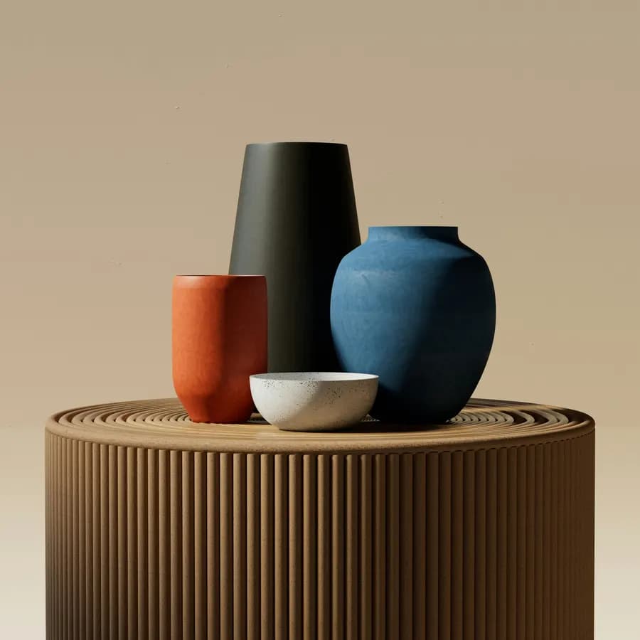 Four matte vases in charcoal, rust and deep blue arranged on a fluted wooden pedestal.